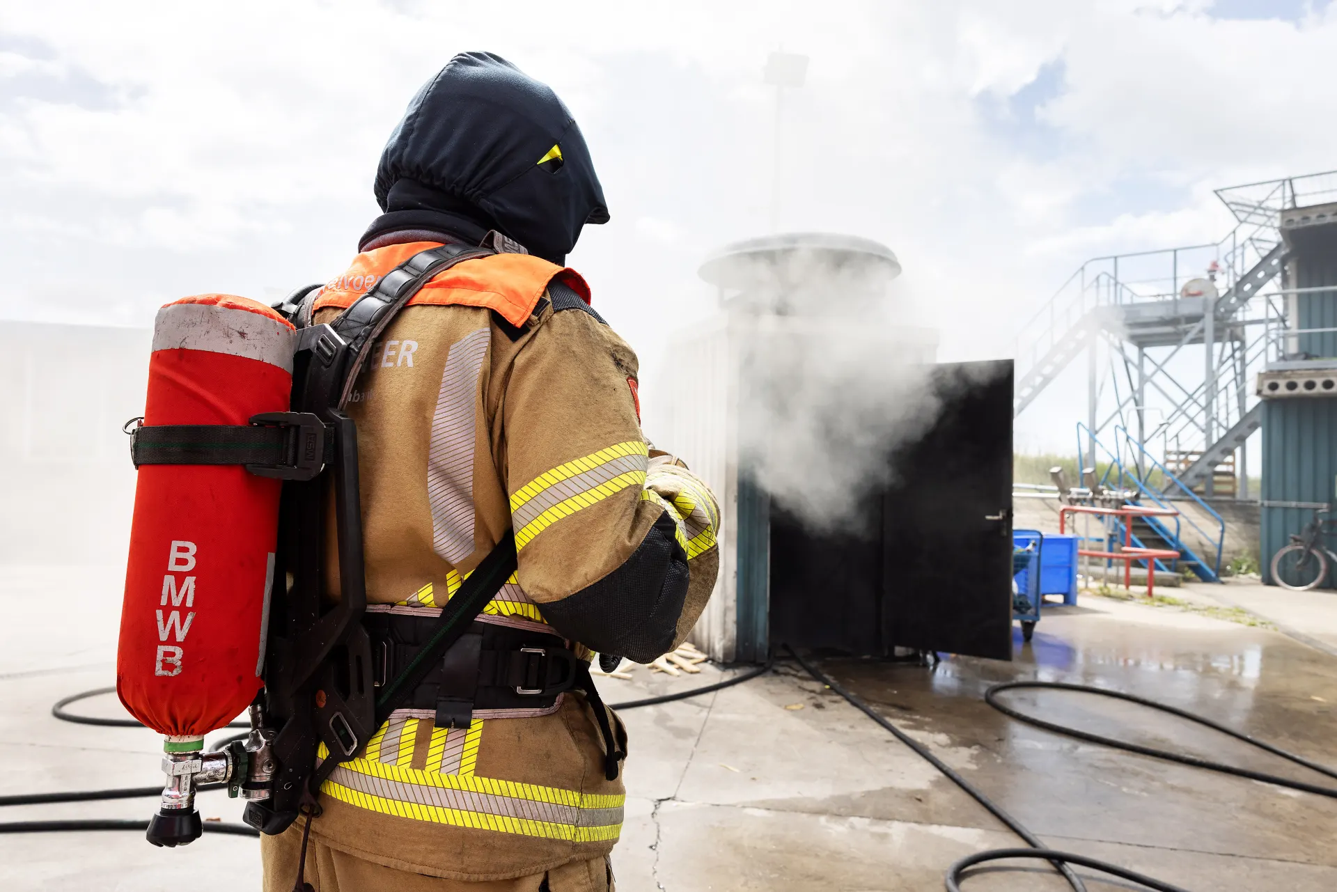 Brandweerman met ademlucht in volledige uitrusting bij een rokende oefenruimte